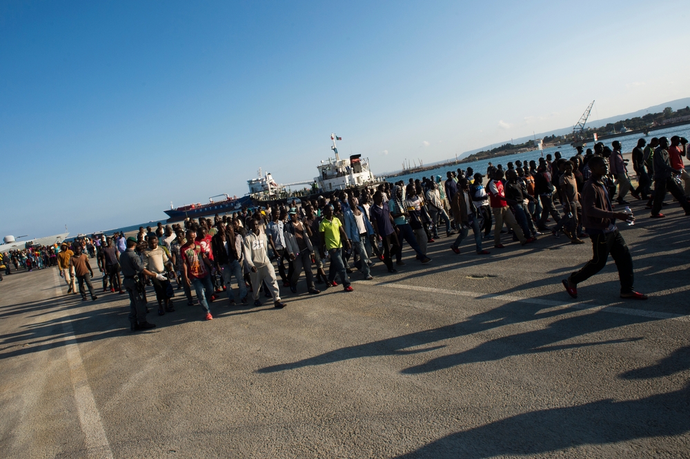Περισσότεροι από 300 μετανάστες, αιτούντες άσυλο και πρόσφυγες, κυρίως από την Ερυθραία και την Γκάμπια, κατευθύνονται προς τον καταυλισμό προσφύγων, μετά την αποβίβαση στο λιμάνι της Αγκούστα στη Σικελία. Ο πόλεμος και οι παρατεταμένες κρίσεις, συμπεριλαμβανομένου του βίαιου χάους που επικρατεί στη Λιβύη, έχουν ωθήσει έναν άνευ προηγουμένου αριθμό ανθρώπων στη θάλασσα ως τη μόνη επιλογή για να φτάσει στην Ευρώπη. Αυτή είναι η πιο επικίνδυνη από όλες τις οδούς μετανάστευσης, όχι μόνο λόγω του κινδύνου να πεθάνουν στη θάλασσα αλλά και για την ακραία βία που συχνά υφίστανται κατά τη διάρκεια του ταξιδιού ιδίως οι περισσότερο ευάλωτοι, όπως είναι οι γυναίκες και τα παιδιά.