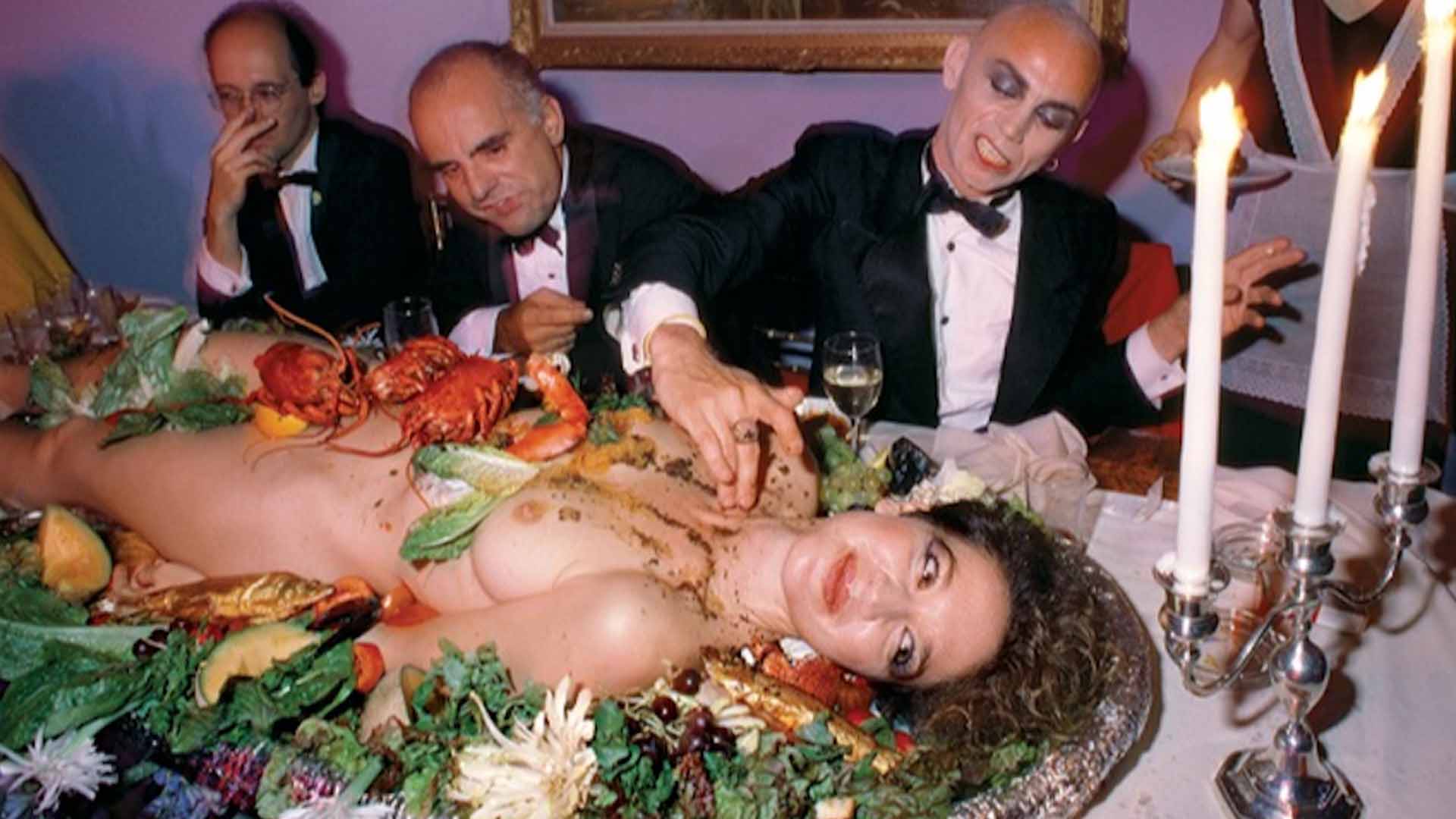 Οι συγγραφείς Luc Sante και Maurizio Torrealta παίρνουν το γεύμα τους μαζί με τον καλλιτέχνη Peter Stack από το γυμνό σώμα της Magdalen Pierrakos.